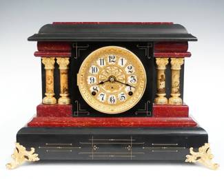 A turn of the century Seth Thomas Milo model Adamantine mantel clock.  8-day time and strike movement with papered metal dial, Arabic numerals, fancy sash and bezel.  Black Adamantine finish with Red moldings and marbleized columns, gold metal castings.  Paper label on back 60% intact.  Case cleaned and polished with slight wear, castings re-painted, running when cataloged.  12" high.  ESTIMATE $150-200