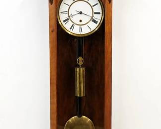 A 19th century Vienna Regulator wall clock.  30-day weight driven time only movement with a two-part porcelain dial, Roman numerals and molded Brass bezel, serial #105968.  Transitional Mahogany case with a carved foliate crest over a molded crown and a single long door with arched glass and carved corner brackets, shaped lower drop.  Refinished with minor wear, faint hairlines in dial, restored crest and drop finial, running when cataloged.  42 3/4" high overall.  ESTIMATE $600-800