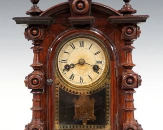A 19th century E. N. Welch Patti No. 2 model Victorian shelf clock, aka "Baby Patti". 8-day dual spring driven time only movement with papered metal dial and Roman numerals and gilded cast pendulum. Rosewood case with arched top and turned finials above a single arched door with stenciled glass, flanked by turned columns on a molded base. Facsimile paper label on back. Older finish with minor wear, dial discoloration, running when cataloged. 10 1/4" high. ESTIMATE $800-1,200