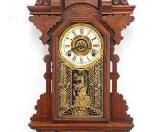 A turn of the century Ingraham St Clair model Kitchen wall clock, retailed by Charles F. Adams, Erie, PA.  8-day time, strike and alarm movement with papered metal dial and Roman numerals.  Walnut case with pressed design features a shaped crest over a molded door with stenciled glass above a shaped bracket drop.  Paper label on back 80% intact.  Older refinishing with minor wear, re-papered dial, running when cataloged.  29" high.  ESTIMATE $100-150