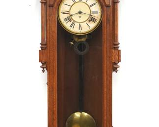 A late 19th century Ansonia Bagdad model wall clock.  8-day time and strike spring driven movement with papered metal dial and Roman numerals  Oak case with carved detail features a shaped crest over an arched door with molded frame flanked by partial turned columns over a shaped lower drop.  Paper label on back 50% intact.  Original finish with some wear, dial wear and discoloration, running when cataloged.  49 1/2" high overall.  ESTIMATE $300-500