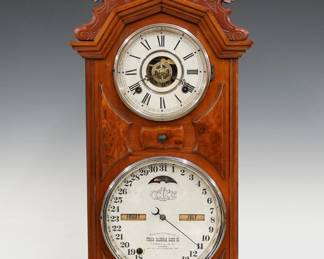 A late 19th century Ithaca No. 8 Library Model shelf clock.  8-day time, strike and alarm movement with lower calendar mechanism and apertures indicating day and month, papered metal dials with Roman/Arabic numerals.  Walnut case with a carved floral crest above circular dial glasses with Nickel bezels and Burl panels on a molded base.  Refinished with slight wear, replaced crest and backboard, re-papered lower dial, running when cataloged.  26 1/2" high.  ESTIMATE $300-400