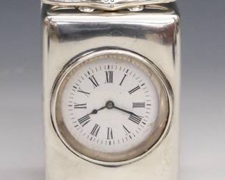 A turn of the century English Sterling boudoir clock. 30 hr movement with platform escapement and porcelain dial with Roman numerals in a Sterling Silver case with hinged rear door. Birminghan Hallmarks with "GB" makers mark. Minor wear, hairlines in dial, running when cataloged. 3" high. ESTIMATE $200-300