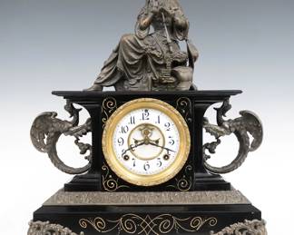 A late 19th century Ansonia Belgium model iron mantel clock.  8-day time and strike movement with visible escapement and two part porcelain dial with Arabic numerals.  Black enameled iron case with cast Spelter topper, gryphons, molding and feet.  Polished finish with some wear, running when cataloged.  19 3/4" high overall.  ESTIMATE $300-400