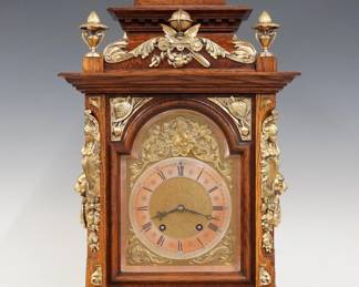 A late 19th century Lenzkirch Table clock.  8-day spring driven time and strike movement with Brass dial, Silvered Chapter ring, cast spandrels and Roman numerals, serial #999035 indicates a production date of 1893.  Oak case with molded detail features gilded cast Brass finials, appliques and gallery arched molded crown over an arched dial door with beveled glass flanked by Carytid corner posts and Lion's Mask side handles on scrolled foliate feet.  Refinished with slight wear, minor wear on chapter ring, running when cataloged.  25 1/4" high overall. ESTIMATE $1,500-2,500
