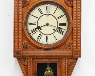 A late 19th century Waterbury Pendant model wall clock.  8-day spring driven time and strike movement with papered metal dial and Roman numerals.  Oak case with carved detail features a shaped crest and turned finials over a circular dial door flanked by carved pilasters and a lower door and shaped drop.  Paper labels inside and on back 60% plus intact.  Older refinishing with minor wear, dial re-papered, running when cataloged.  28 1/2" high.  ESTIMATE $200-300