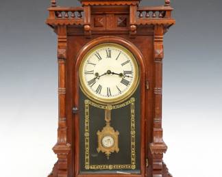 A 19th century E. N. Welch Nilsson model Victorian shelf clock. 8-day time and strike movement with painted metal dial and Roman numerals, fancy pendulum with glass insert. Walnut case with shaped gallery top and turned finials above a single arched door with stenciled glass, flanked by fluted pilasters on a molded base. Paper label on back 80%. Older finish with minor wear, running when cataloged. 21 3/4" high. ESTIMATE $300-400
