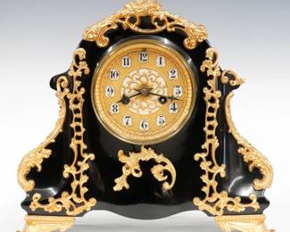 A late 19th century Waterbury iron mantel clock.  8-day time and strike movement with gold sash dial with Arabic numerals.  Black enameled iron case with applied Gold painted castings and feet.  Polished finish with slight wear, re-painted Gold, running when cataloged.  11 3/4" high.  ESTIMATE $100-200