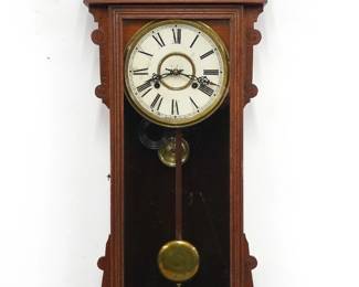 A late 19th century Waterbury Bruce model wall clock.  8-day spring driven time and strike movement with papered metal dial and Roman numerals.  Oak case with carved detail features a shaped spindle work crest over a door with molded frame flanked by shaped ears and shaped gallery drop.  Paper label on back 50% intact.  Old finish with minor wear, dial wear, running when cataloged.  38" high.  ESTIMATE $200-300