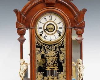 A late 19th century Ansonia Windsor model mirror side shelf clock.  8-day time, strike and alarm movement with papered metal dial and Roman numerals.  Walnut case with a carved arched crest above an arched door with stenciled glass flanked by mirrored pilasters and cast cherub figures on a molded base with cast feet.  Refinished with minor wear, re-papered dial, replaced cherubs, running when cataloged.  21 1/2" high.  ESTIMATE $200-300