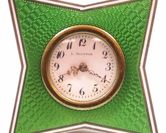 An early 20th century Louis Vuitton travel clock. Porcelain dial with Arabic numerals and filigree hands in a Green guilloche enameled frame with hinged rear leg. Minor wear, small repair to leg hinge, running when cataloged. 2" high. ESTIMATE $300-400