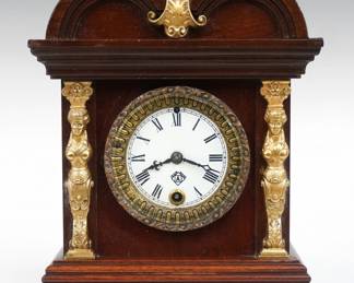 A late 19th century Ansonia boudoir clock.  30-hr time only movement with porcelain dial and Roman numerals.  Mahogany case with double arch top and applied cast decorations on a molded base.  Minor wear, running when cataloged.  11 1/2" high.  ESTIMATE $50-75