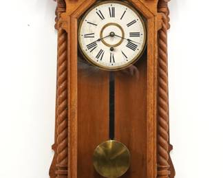 A turn of the century Ansonia Queen Anne model wall clock.  8-day time only movement with papered metal dial and Roman numerals.  Oak case with a shaped crest and turned finials over a molded door flanked by turned rope columns over a shaped bracket drop with turned rail.  Older refinishing with minor wear, some dial wear, running when cataloged.  40" high.  ESTIMATE $200-300