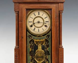 A late 19th century New Haven Douro model shelf clock.  8-day time and strike movement with papered metal dial and Roman numerals.  Walnut case with molded crest and central peak above an molded door with stenciled glass flanked by turned double columns on a molded base.  Paper label on back 50 % intact.  Refinished with minor wear, re-papered dial, running when cataloged.  21 1/2" high.  ESTIMATE $100-150
