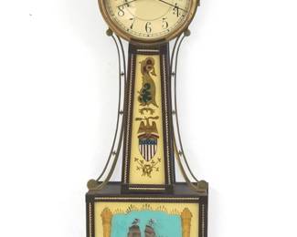 A 1930's Waltham "Willard" model Presentation Banjo clock. 8-day weight driven time only movement with painted Iron dial with Arabic numerals marked "Waltham". Mahogany case features a turned finial over a molded Brass dial door and tapered throat panel with reverse painted glass flanked by scrolled Brass side arms and lower door with reverse painted "Constitution & Guerriere" Naval Battle glass, over a shaped, fluted drop all with applied Brass roped detail. Original finish with minor wear, slight dial wear, running when cataloged. 40 1/2" high overall. ESTIMATE $600-800