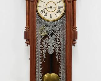 A late 19th century Ansonia Bagdad model wall clock.  8-day time and strike spring driven movement with papered metal dial and Roman numerals  Oak case with carved detail features a shaped crest over an arched door with molded frame and stenciled glass flanked by partial turned columns over a shaped lower drop.  Paper label on back 10% intact.  Refinished with slight wear, dial restored , running when cataloged.  49 1/2" high overall.  ESTIMATE $300-400