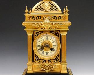 A turn of the century French mantel clock by "A. D. Mougin, Paris". 8-day time and strike movement, painted porcelain dial, Roman numerals and gilded dial center. Gilded Bronze Louis XVI style case with floral domed top with mask detail and reticulated gallery, fluted column with cast scrollwork panels on a Black Slate base with molded bracket feet. Minor wear, dial hairlines, running when cataloged. 16 1/4" high. ESTIMATE $600-800