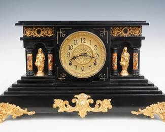 A turn of the century Ingraham Sonata model mantel clock.  8-day time and strike movement with embossed Brass dial, Arabic numerals.  Black enamel finish with marbleized columns, gold metal castings.  Paper label on back 80% intact.  Case refinished with slight wear, castings re-painted, running when cataloged.  12 1/4" high.  ESTIMATE $150-200