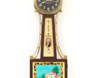 A 1930's miniature Waltham Presentation Banjo clock, Washington/Mt Vernon model.  8-day time only stem wind movement with lever escapement and Black painted dial with Arabic numerals, subsidiary seconds.  Mahogany case with Brass Eagle finial and side arms, reverse painted throat glass and lower glass.  Original finish with wear and crazing, replaced lower glass, running when cataloged.  20 3/4" high.  ESTIMATE $100-150