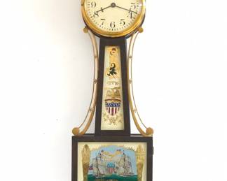 A 1930's miniature Waltham Presentation Banjo clock. 8-day time only stem wind movement with lever escapement and painted dial with Arabic numerals.  Mahogany case with Brass Eagle finial, side arms and rope trim, reverse painted throat glass and lower glass.  Original finish with wear and crazing, replaced lower glass by D. Lima, running when cataloged.  20 3/4" high.  ESTIMATE $100-150