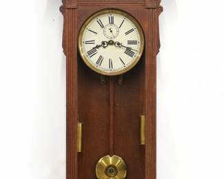 A late 19th century Waterbury Regulator No. 53 model wall clock.  8-day time only dual weight driven movement with painted metal dial, Roman numerals and subsidiary seconds.  Fancy Oak case with carved detail features a galleried crest with central medallion and turned finials over an arched door with molded frame and a lower bracket drop with turned spindles and drop finials.  Original finish with some wear, dial wear and small touch-ups, running when cataloged.  53 1/2" high overall.  ESTIMATE $800-1,200