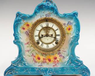 A late 19th century Ansonia La Lorne model porcelain shelf clock.  8-day time and strike movement with visible escapement, two part porcelain dial and Roman numerals.  Molded porcelain case with floral decoration on a Blue background with gilded detail.  Minor wear, some crazing, running when cataloged.  11 1/2" high.  ESTIMATE $200-300