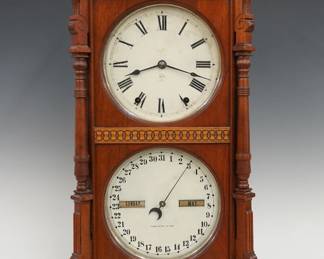 A late 19th century Seth Thomas Parlor Calendar No. 8 model shelf clock.  8-day time and strike movement with lower calendar mechanism, painted metal dials with Roman/Arabic numerals and apertures indicating day and month.  Walnut case with a carved crest and turned finials over a single door with circular dial glasses and applied geometric moldings flanked by turned pilasters on a molded base.  Paper label on back of door 60% intact.  Older refinishing with minor wear, small chips on finials and crown return, minor dial flaking, running when cataloged.   27 1/2" high overall.   ESTIMATE $600-800