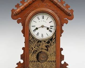 A late 19th century Welch Daisy model shelf clock.  30-hr time and strike movement with papered metal dial and Roman numerals.  Walnut case with a shaped crest and turned detail over an arched door and a simple plinth base.  Fragment of paper label on back.  Older finish with some wear, minor dial wear, running when cataloged.  19" high.  ESTIMATE $50-75