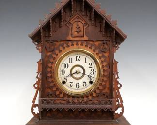 A late 19th century Frankf(i)eld & Co. New York, Black Forest style cuckoo shelf clock.  Waterbury 8-day time and strike movement adapted by Frankfield with bellow lift wires and cuckoo arm, papered metal dial and Arabic numerals, stamped "Frankfeld & Co.".  Mixed wood chalet style case with original two tone finish with fret sawn components features a gabled roof, molded Brass dial door and fretwork balcony on a shaped bracket base.  Some wear, re-papered dial. running and functioning when cataloged.  23 1/2" high.  ESTIMATE $400-600