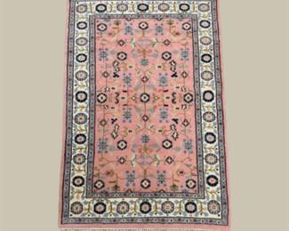 Soft salmon and ivory rug with a geometric center and contrasting circular border details.
