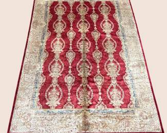 Decorative red and ivory rug with repeating ornamental motifs and a patterned border.