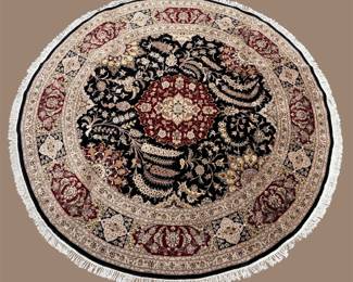 Round traditional rug with a dramatic central motif, layered borders, and decorative fringe.