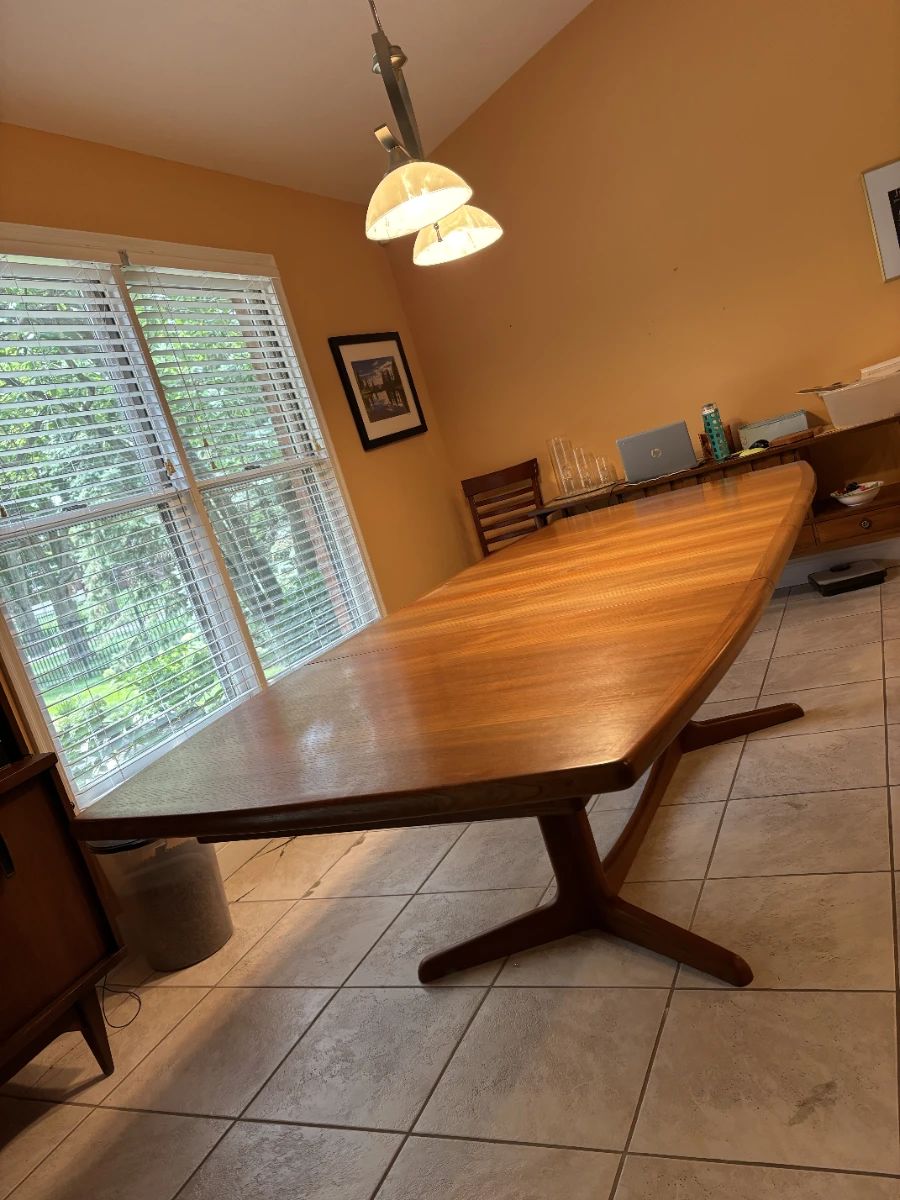 MCM Teak Dining table with minimalist split pedestal base.  Created by Josef Otmar in the Danish Style during the 1960's. Includes 2 original self storing table leafs. Styled after Gudme Mobelfabrik or Benny Linden brands of Denmark.  Purchased at Otmar.  Owner was friends with Mr Otmar.
