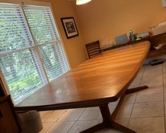 MCM Teak Dining table with minimalist split pedestal base.  Created by Josef Otmar in the Danish Style during the 1960's. Includes 2 original self storing table leafs. Styled after Gudme Mobelfabrik or Benny Linden brands of Denmark.  Purchased at Otmar.  Owner was friends with Mr Otmar.
