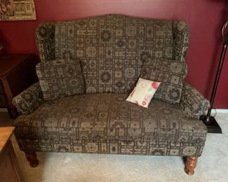 High back loveseat in dark greens and browns. Sits firm