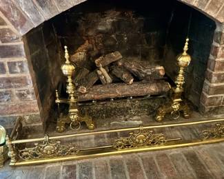 Ornate fireplace set featuring 2 polished brass Andirons and matching brass fender across hearth