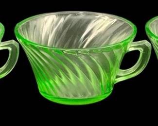 380 - 3 Uranium Green Glass Cups 2"x4" (Description): A three-piece set of uranium glass cups  featuring a swirled ribbed pattern. The  translucent green glass exhibits the  characteristic glow of uranium glass. Each  cup measures 2 inches by 4 inches.