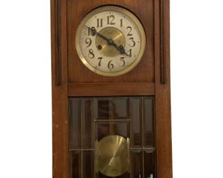 672 - Antique Wall Clock 27"x15"x7" (Description): Antique wall clock in a wooden case with  decorative carved crest and leaded glass door  panel revealing the pendulum. The clock face  features Arabic numerals. Glass is cracked.  Measures 27 inches high by 15 inches wide by 7 inches deep. Used as is electric/electronic/mechanical  item. No guarantee all components, untested.