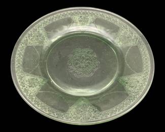 533 - Uranium Green Glass Plate 8.5" (Description): Uranium glass plate measuring 8.5 inches in  diameter. The plate features a pressed  decorative pattern with a central medallion  design and ornate geometric detailing around  the rim.