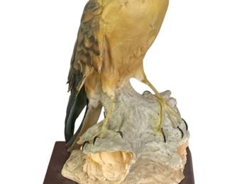44 - Hand-painted Hawk Figurine (Description): Hawk statue depicting a bird of prey perched  on a naturalistic rock formation. The piece  is mounted on a wooden base with a brass  nameplate. Measures 13 inches by 14.5 inches  by 10 inches.