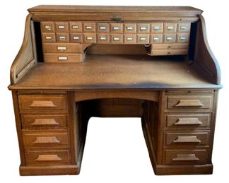 118 - Antique Roll-Top Desk 49.5"x60"x34" (Description): Antique roll-top desk featuring a traditional  S-curve tambour top with numerous small  interior drawers and compartments. The desk  has two pedestals, each fitted with multiple  drawers featuring carved wooden pulls. Measures 49.5 inches high by 60 inches wide  by 34 inches deep.