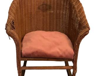 149 - Child's Wicker Rocker 19.5"x20.5"x14.5" (Description): A wicker rocker featuring a rounded  barrel-style back with wrapped frame  detailing. The chair includes a cushioned  seat. Measures 19.5 inches by 20.5 inches by  14.5 inches.