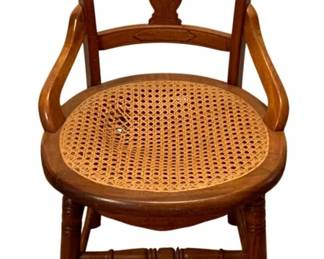 696 - Antique Cane Seat Chair 33.5"x18"x17" - as is (Description): Antique wooden chair featuring a cane seat.  The chair displays carved detailing on the  backrest with a central splat and curved top  rail. It has gracefully curved arms and  turned legs with stretchers. Measures 33.5x18x17