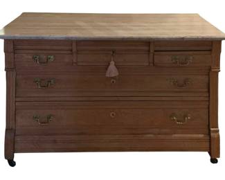 137 - Marble-Top Chest 32"x48.5"x23" (Description): Marble-top chest measuring 32 inches high by  48.5 inches wide by 23 inches deep. Features  multiple drawers with decorative brass bail  handles and keyhole escutcheons. The chest  rests on casters for mobility.