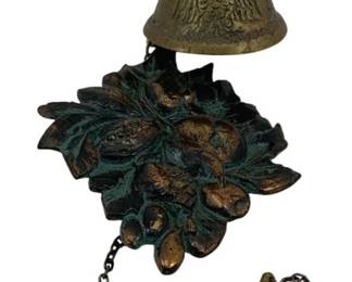 528 - Brass Bell 4.5"x8"x5" (Description): A decorative brass bell featuring ornate  design elements. The bell includes a chain  pull mechanism and displays detailed  metalwork with a verdigris patina finish.  Measures 4 1/2" x 8" x 5".