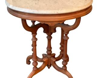 73 - Marble Top Table 28.5"x24"x18" (Description): Marble top table featuring an oval white  marble surface set upon an ornate carved  wooden base with turned legs and decorative  stretchers. Measures 28.5 inches by 24 inches  by 18 inches.