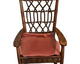 155 - Antique Wicker Rocking Chair 28"x16"x15" (Description): Antique wicker rocking chair featuring a  woven lattice back with turned wooden finials  and paddle-shaped wooden arms. The chair  measures 28 inches by 16 inches by 15 inches  and includes a cushion.