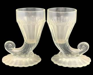 333 - 2 Clear Glass Cornucopias 5.5"x4"x3" (Description): A two-piece set of clear glass cornucopias.  Each piece features a horn of plenty design  with a ribbed body and decorative scrolled  base. Measurements: 5 1/2" x 4" x 3".