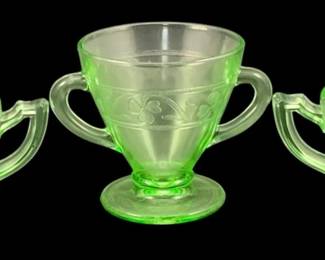 379 - 3 Uranium Green Glass Items (Description): A three-piece lot of uranium glass cups  featuring decorative pressed patterns. The  set includes two matching cups and one footed  double-handled sugar bowl, all crafted in  characteristic green uranium glass. Measurements: 3.5"x4.5"x3.25".