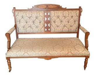 71 - Antique Victorian Eastlake Style Settee (Description): Antique settee eaturing an ornately carved  wooden frame with decorative crest rail and  fretwork details. The piece is upholstered in  a damask fabric with tufted back panels and  padded armrests. Supported on turned legs with casters. Measures 40 inches high by 53  inches wide by 23 inches deep.